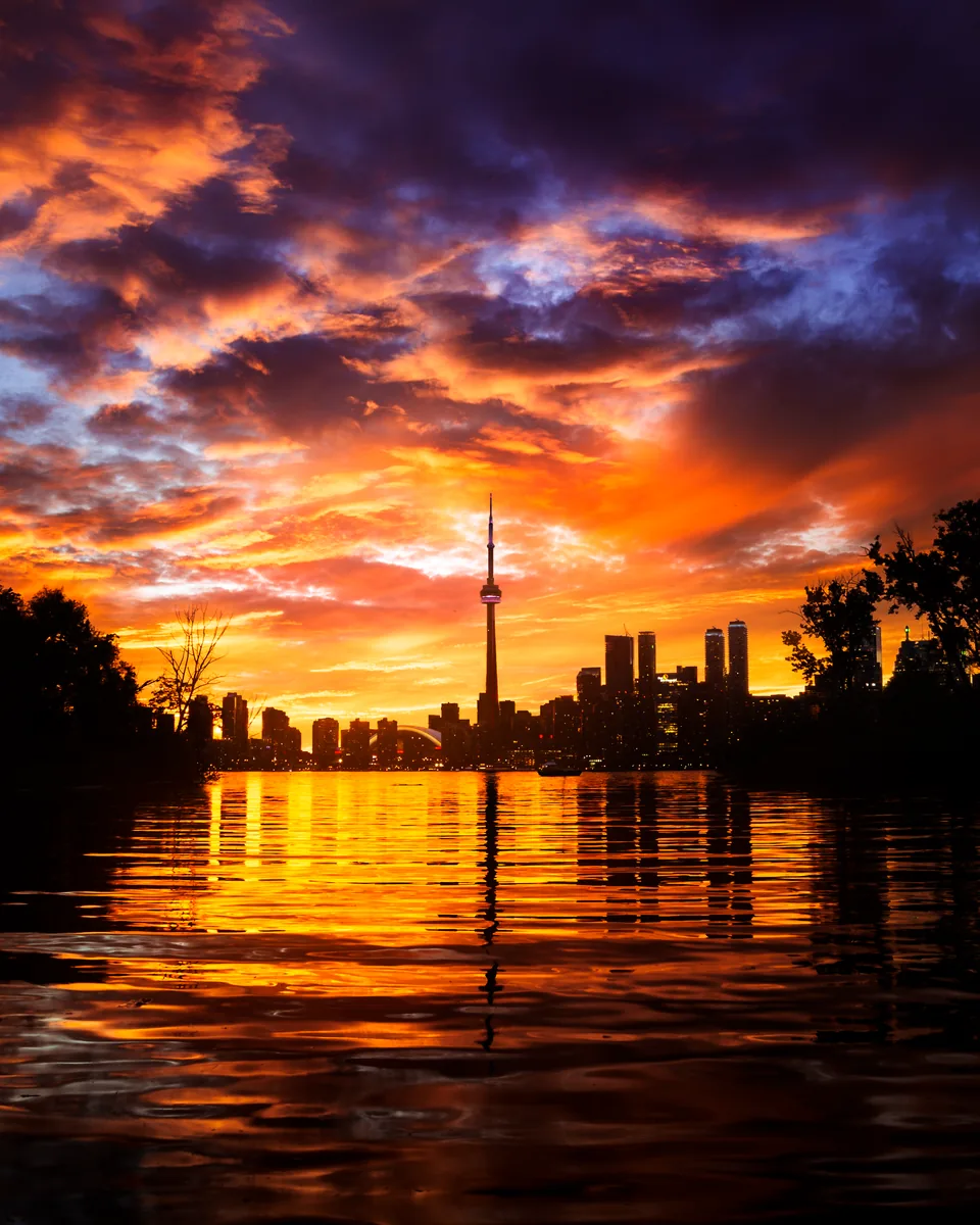Silent Skies, streaking sunset clouds over the Toronto skyline and CN Tower, reflected in still water at Sunfish Cut