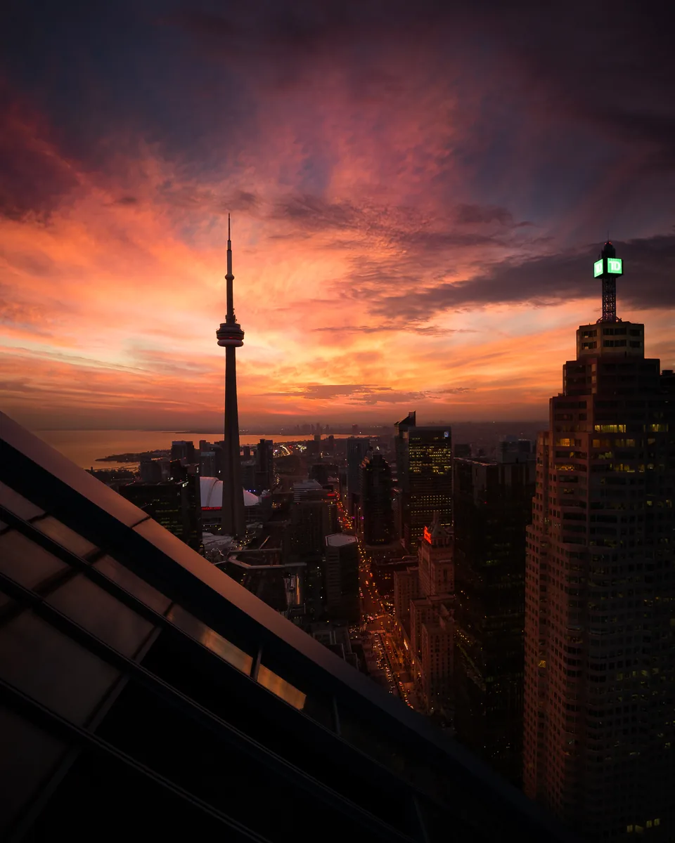 The CN Tower and downtown Toronto towers under an orange and red sunset sky