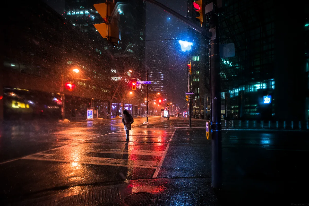 Nobody, a lone figure crossing a snowy street at night in Toronto's Financial District