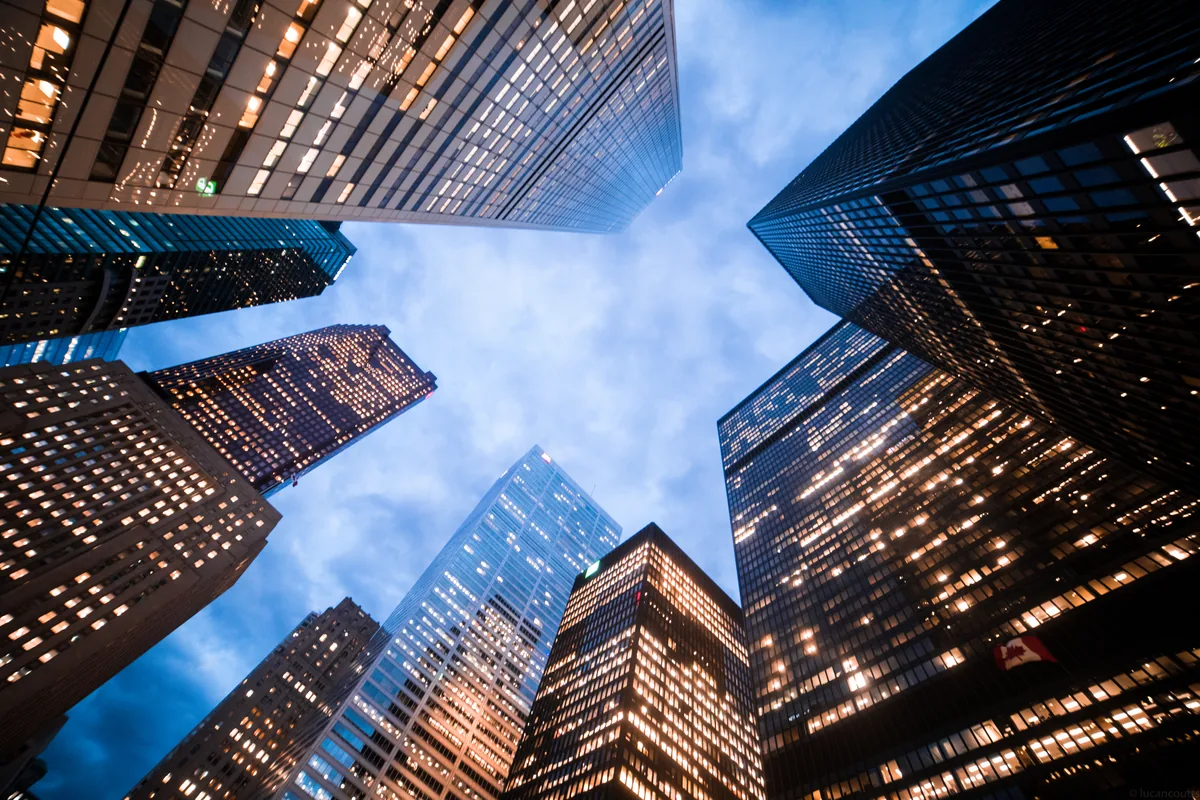 Looking straight up between the glass skyscrapers of Toronto's Financial District into a blue sky
